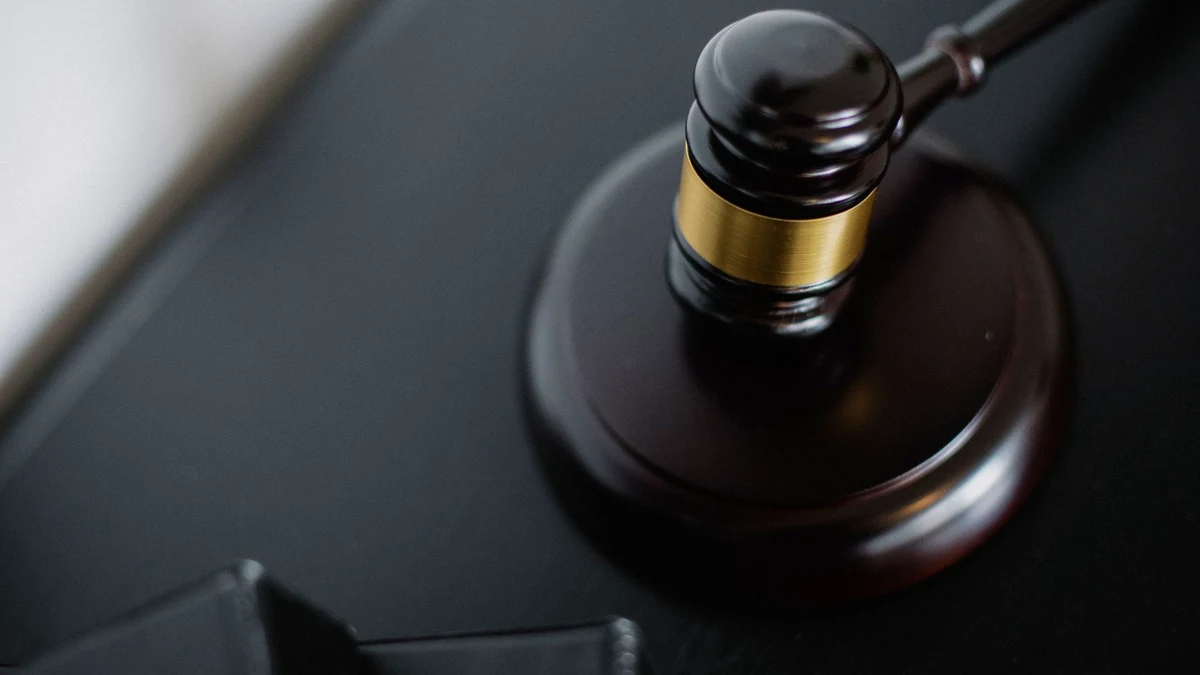 Marteau de juge posé sur son socle, sur un bureau sombre